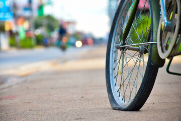 The rear wheel of the bicycle is flat and is left parked on the sidewalk to change and fix it.