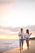 © New Africa - Lovely couple with glasses of wine walking on beach at sunset. Space for text