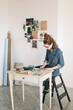 © Alberto Bogo/Stocksy - Focused Young Woman Choosing Color Sample For Moodboard On Wooden Table