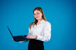 © Iryna - Portrait of young smiling white european woman wearing white t-shirt and holding the laptop on a blue background