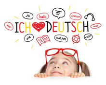 Beautiful Cute Little Girl With Eyeglasses Looking At Ich Liebe Deutch Text (English Translation: I Love German) And Illustrations..