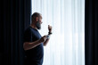 © DSMT - An adult man with a beard drinks coffee and looks out the window. Working day field recreation concept