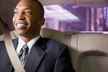 African Businessman Wearing Seatbelt In Back Seat Of Car