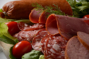 Wall Mural - A selection of spicy dried or smoked  sausages on lettuce leaves with cherry tomatoes