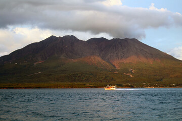 Closeup view of ferry passing by Sakurajima during sunse