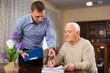© JackF - Adult man helping his senior father filling out financial documents at home
