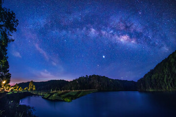 Wall Mural - milky way galaxy on mountain reservoirs and pine forests long exposure photograph, with grain.image 