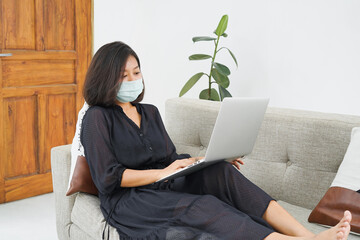 Asian women working from home during the corona virus pandemic. Asian women work while wearing masks