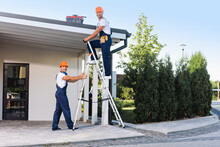 Builders In Uniform Using Ladder Near Building Outdoors