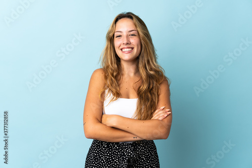 Fotomural Young blonde woman isolated on blue background keeping the arms crossed in front