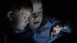 © MEDIAIMAG - Two brothers look at tablet screen in dark, sibling dispute