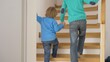 © MEDIAIMAG - Little child holding big brother hand and go upstairs, family support