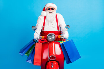 Wall Mural - Photo of stylish modern crazy white grey hair bearded santa claus drive x-mas christmas scooter hold bags wear red costume suspenders overalls isolated over blue color background