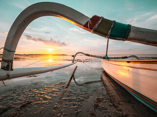 Wall Mural - Indonesian fishing boat on the beach at low tide. Strong sunset colors and reflections and reflections in the water