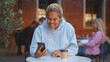 © nimito - Excited african woman receiving good email on smartphone and smiling sitting in cafe