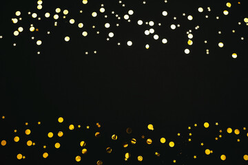 Gold and silver confetti on a black festive background. In the middle there is space for text or copy space.