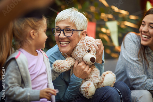 Cuadros en Lienzo grandmother holding teddy bear, playing with her granddaughter