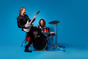 Full length photo two funky popular rock band perform new composition man play guitar woman drum drumstick enjoy punk night club tour wear leather jacket isolated bright color background