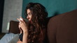 © stockbusters - Young lady drinking coffee in bedroom. Long hair woman enjoying hot drink in bed