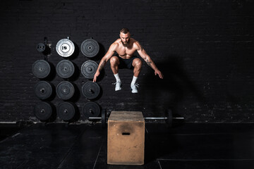 Young strong fit sweaty muscular man with big muscles doing box jump workout in the gym as hardcore cross training