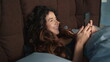 © stockbusters - Happy woman using mobile phone in bed. Cheerful girl looking cellphone screen.