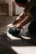 Male hands are working with a wooden floor. In the hands of a sander.