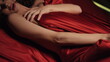 © stockbusters - Sexy woman hands playing red silk sheet in bed. Naked girl relaxing in bedroom.