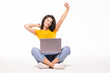 © F8  \ Suport Ukraine - Young woman sitting on the floor with a laptop computer and arms up isolated on white background