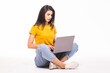 © F8  \ Suport Ukraine - Young woman sitting on the floor and using laptop on white background
