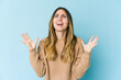 © Asier - Young caucasian woman isolated on blue background screaming to the sky, looking up, frustrated.