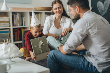 father and mother giving birthday gift to his child at home