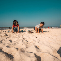 two little brothers having fun playing in the sand on the beach