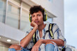 © Cavan Images - Boring young afro with headphones on sitting on the street
