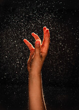 Hand Reaching Into The Sparkling Mist Against A Black Background.