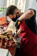 Butcher With Mask Preparing And Cutting Meat