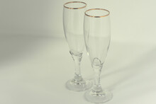 Preparing The Table For An Important Event. Two Clear Crystal Glasses With Pure Gold Rim On A White Background.