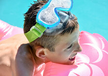 Portrait Of A Blonde Boy Wearing Blue And Green Diving Goggles At Bath