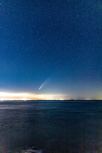 Comet NEOWISE Streaking Through The Starry Night Sky Above The Ocean.