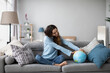 © BestForYou - Happy smiling woman with a globe model sitting on the couch at home. Travel planning.