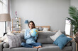 © BestForYou - Happy smiling woman with a globe model sitting on the couch at home. Travel planning.