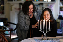 Hanukkah: Girl And Mother Admire Lit Candles