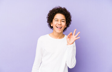 Wall Mural - African american little boy isolated winks an eye and holds an okay gesture with hand.