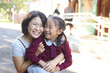 © Claire Bonnor/Austockphoto - School girl sitting on her mother's knee, smiling and laughing