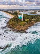 Aerial View Of A Lighthouse And A Water Tank On A Clifftop Above Crashing Waves