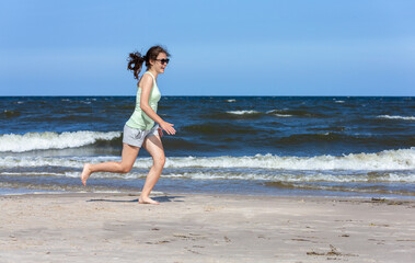 Wall Mural - Teenage girl running, jumping on beach
