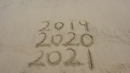 Wall Mural - 2021 and 2020 inscription written in the wet beach sand with sea water wave.