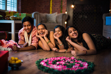 Indian Kids celebrating Diwali / Deepawali, Bhai Dooj or Rakhi / Raksha Bandhan with flower rangoli, gifts, diya