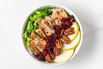 Wall Mural - healthy chicken lunch bowl salad. Chicken breast, pear, pecan nuts and dried berries autumn salad. Top view