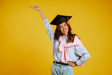 Portrait of Graduate woman in a graduation hat on her head.  Study, education, university, college, graduate concept on yellow banner.