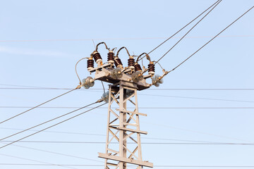 High voltage lines and power pylons in a flat and green agricultural landscape on a sunny day with cirrus clouds in the blue sky. Pylon and transmission power line